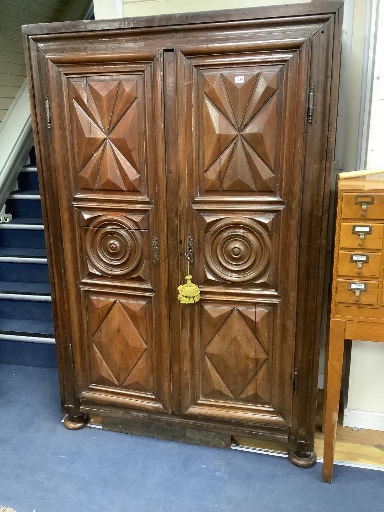 A large fruitwood double wardrobe / armoire, with twin carved panelled doors below a dentil frieze, raised on squat bun feet, 18th century, width 130cm, depth 62cm, height 198cm